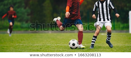 Young Athletes Kicking Soccer Ball On Wet Grass Field ストックフォト © matimix