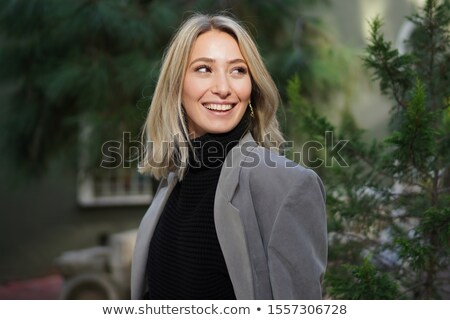Foto d'archivio: Young Beautiful Blonde Girl In Black Sweater On Gray Background