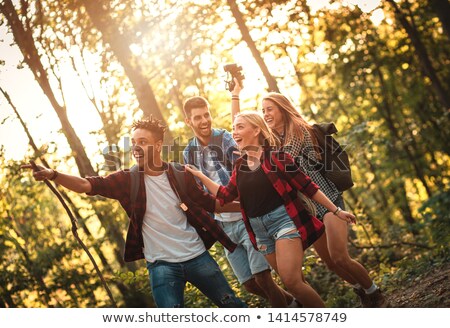 Foto d'archivio: Group Of Four Friends Hiking Together Through A Forest