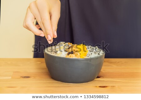 Foto stock: Woman Cooks Smoothie Bowls Made With Mango Banana Granola Grated Coconut Dragon Fruit Chia Seed