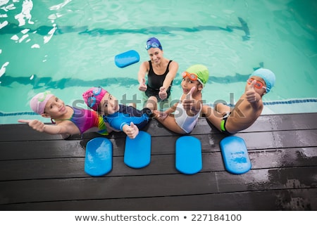 Stockfoto: Male Instructor Swimming For Children Teaches A Happy Boy To Swim In The Pool