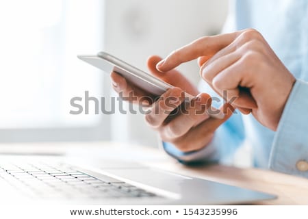 Foto stock: Hands Of Young Businessman Pointing At Smartphone Screen Over Laptop Keypad