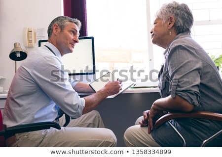 [[stock_photo]]: Side View Of Male Caucasian Doctor Prescribing Medicine To Senior African American Woman In Clinic A