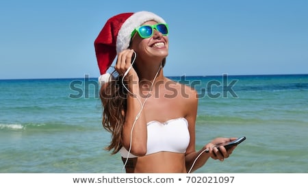 Foto stock: Woman Wearing Santa Claus Hat And Sunglasses Listening To Music