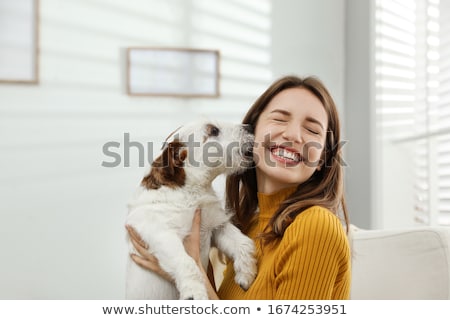 Foto d'archivio: Young Girl Cuddling Her Pet Dog At Home