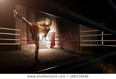 Foto d'archivio: The Young Man Kickboxing On Black Background