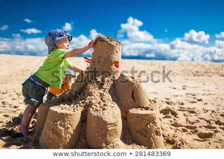 Foto stock: Friends Building Sandcastle On Beach