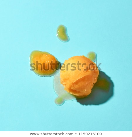 Flat Lay Of A Spoon For Ice Cream With Yellow Mango Dessert And Melted Ice Cream On A Blue Backgroun Stockfoto © artjazz