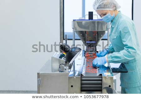 Foto stock: Pharmacy Industry Woman Worker In Protective Clothing Operating Production Of Tablets In Sterile Wor