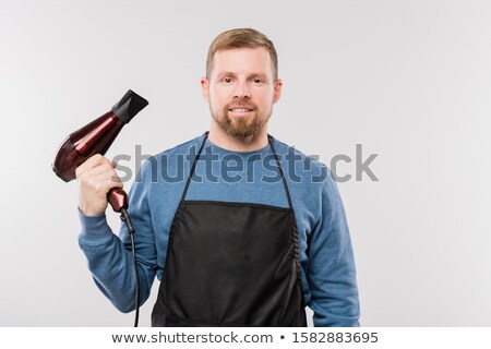 Stock foto: Young Bearded Hairdresser In Apron And Blue Pullover Holding Hairdryer