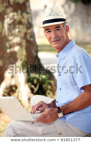 ストックフォト: Middle Aged Man Sat In Park With Laptop