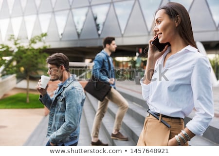 Stockfoto: Businesswoman Walking Down The Street While Talking On Smart Pho