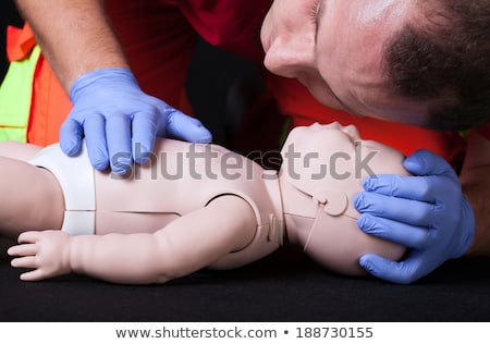 Stockfoto: Paramedic Demonstrating Resuscitation On A Infant Dummy