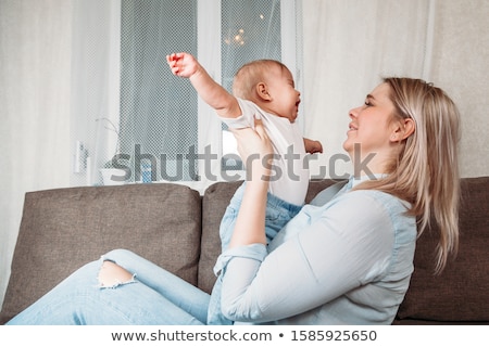 Stok fotoğraf: Young Mother With Baby Daughter On Sofa At Home The Baby Crying