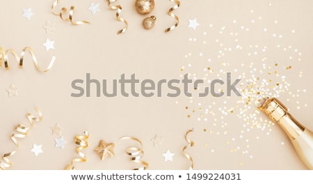 Foto d'archivio: Gold Champagne Bottle With Confetti Stars And Party Streamers