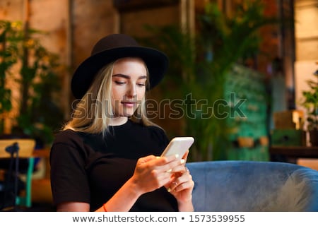 ストックフォト: Blond Girl In White Jeans Skirt Blouse And Black Hat Sitting A