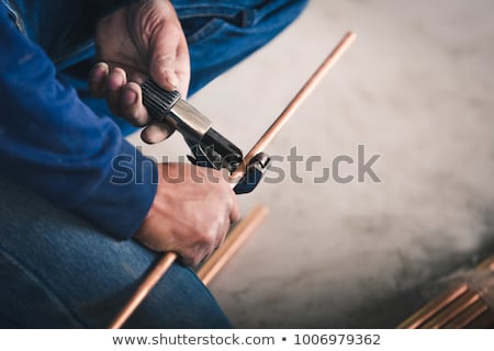 [[stock_photo]]: Plumber Cutting Copper Pipe