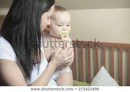 Foto d'archivio: Devoted Mother Laying Son Down Into Crib For Nap In Bedroom