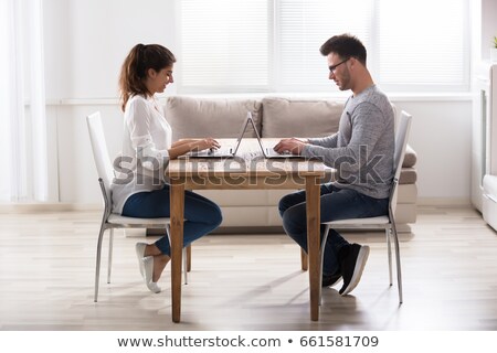 Stock fotó: Young Couple Sitting Face To Face With Laptop