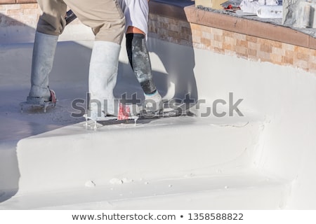 Foto stock: Worker Wearing Spiked Shoes Smoothing Wet Pool Plaster With Trow