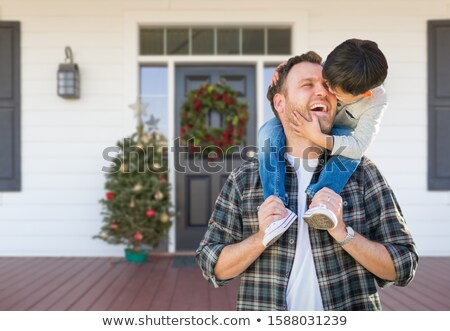 Stockfoto: Young Mixed Race Boy On Front Porch Of House With Christmas Deco