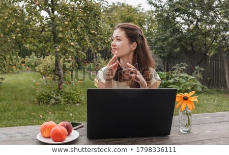 Foto stock: Young Woman With Laptop Sitting On Green Grass And Looking To Th