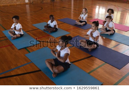 Stok fotoğraf: High Angle View Of Black Schoolboy Doing Yoga And Meditating On A Yoga Mat In School