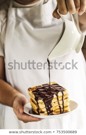 Stockfoto: The Chef In His Hands Holds A Plate With Belgian Waffles And Pou