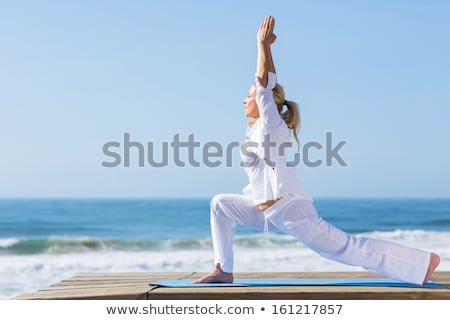 Stok fotoğraf: Senior Woman Doing Yoga On Beach