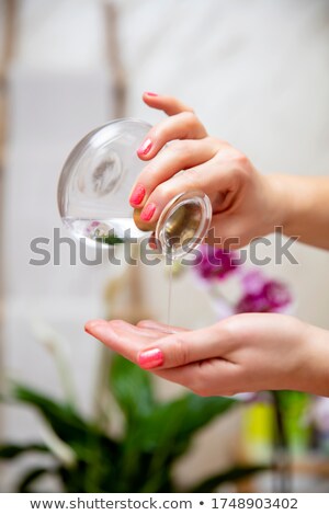 Stock photo: Therapist Pouring Essential Oil From Glass Bottle In Spa