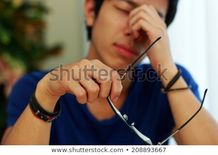 Stock photo: Tired Asian Man With Eye Pain Holding Glasses In Hand Focus On Glasses