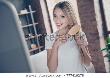 Stock photo: Woman Brushing Her Hair In Front A Mirror