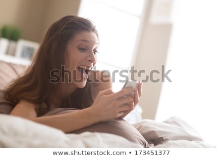 Stok fotoğraf: Young Woman Texting In Bed