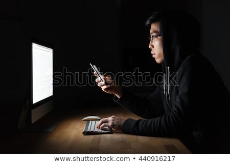 Сток-фото: Hacker Using Laptop And Mobile Phone In Dark Room