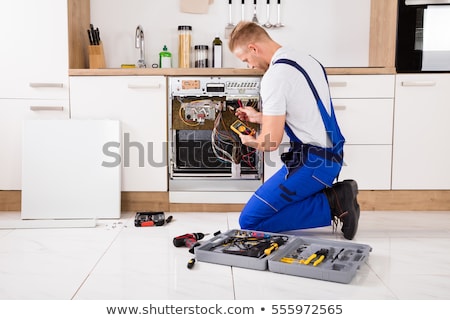 [[stock_photo]]: Repairman Fixing Dishwasher With Digital Multimeter