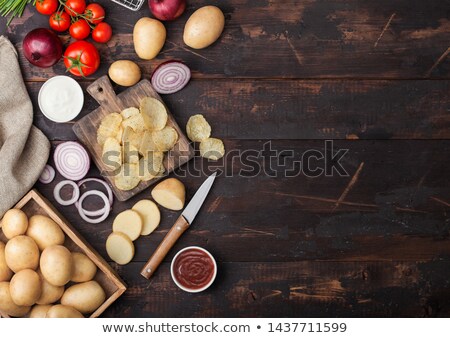 Stock photo: Fresh Organic Homemade Potato Crisps Chips With Sour Cream And Red Onions On Chopping Board On Dark