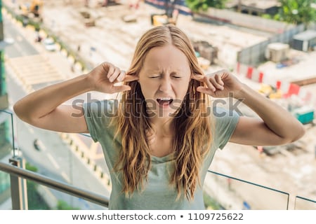 [[stock_photo]]: A Young Woman By The Window Annoyed By The Building Works Outside Noise Concept