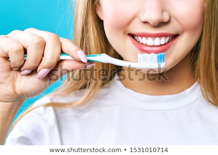 Foto d'archivio: Tooth Holds Toothpaste And Toothbrush