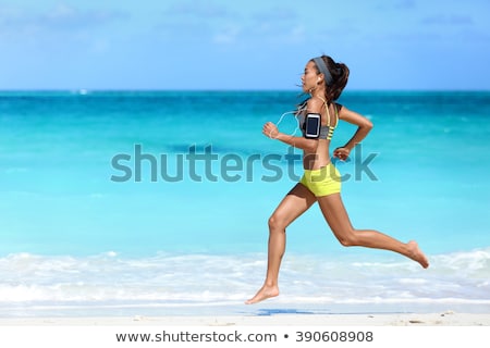 Stock photo: Woman With Earphones And Armband Running On Beach