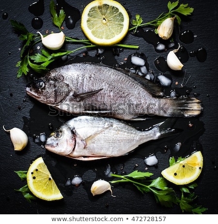 Stockfoto: Fresh Fish Orata Over A Black Stone With Vegetables