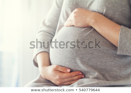 Foto stock: Happy Young Pregnant Woman Holding Her Hands On Her Tummy