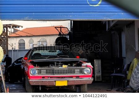 Foto d'archivio: Mechanic Changing Tire From Suspended Car In Garage