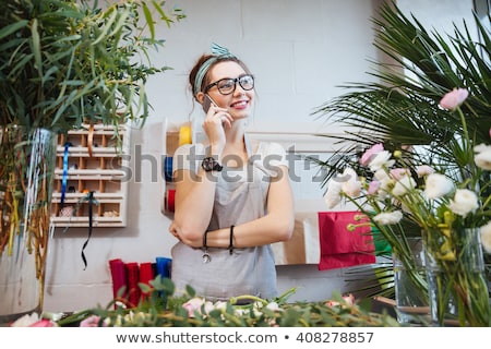 Stockfoto: Cheerful Young Woman Gardener Talking On Mobile Phone