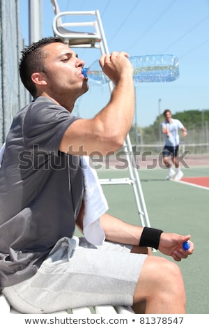 Stok fotoğraf: Man Drinking Water On Tennis Court Sideline