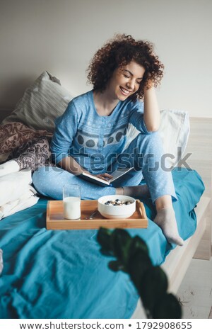 Zdjęcia stock: Pretty Woman In Pajamas Eating Cereals With Milk On Bed