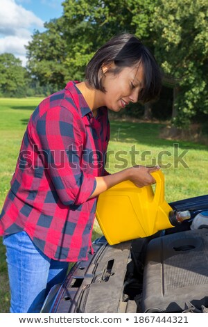Stock photo: Woman Filling Car Motor With Oil In Jerrycan