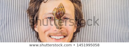 Foto d'archivio: Young Man Makes A Face Mask With Snail Mucus Snail Crawling On A Face Mask Spa For Man Spa For Al