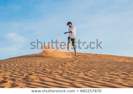 Foto d'archivio: A Man Is Kicking Sand In A Red Desert Splash Of Anger Concept