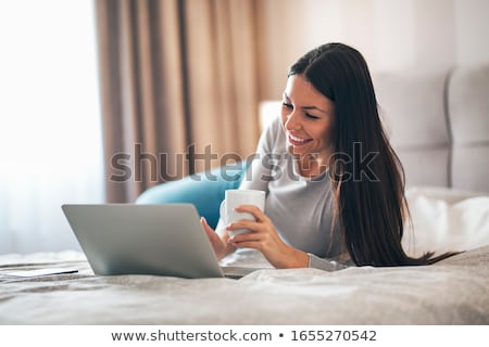 Stockfoto: Businesswoman Using Laptop While Lying On Bed