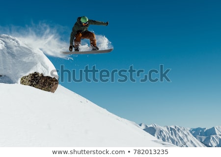 Foto stock: Snowboarder Jumping Off A Rock